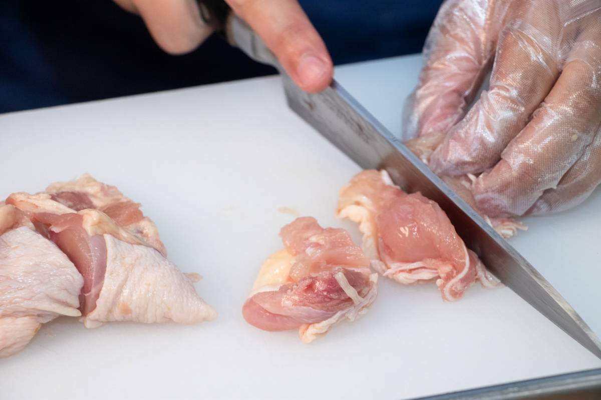 鶏肉を包丁で切っている写真